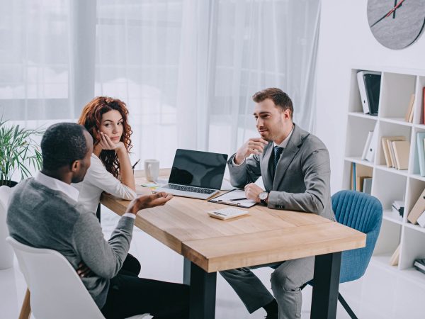 estate-agent-sitting-at-table-with-laptop-and-talk-38E5QZ8.jpg